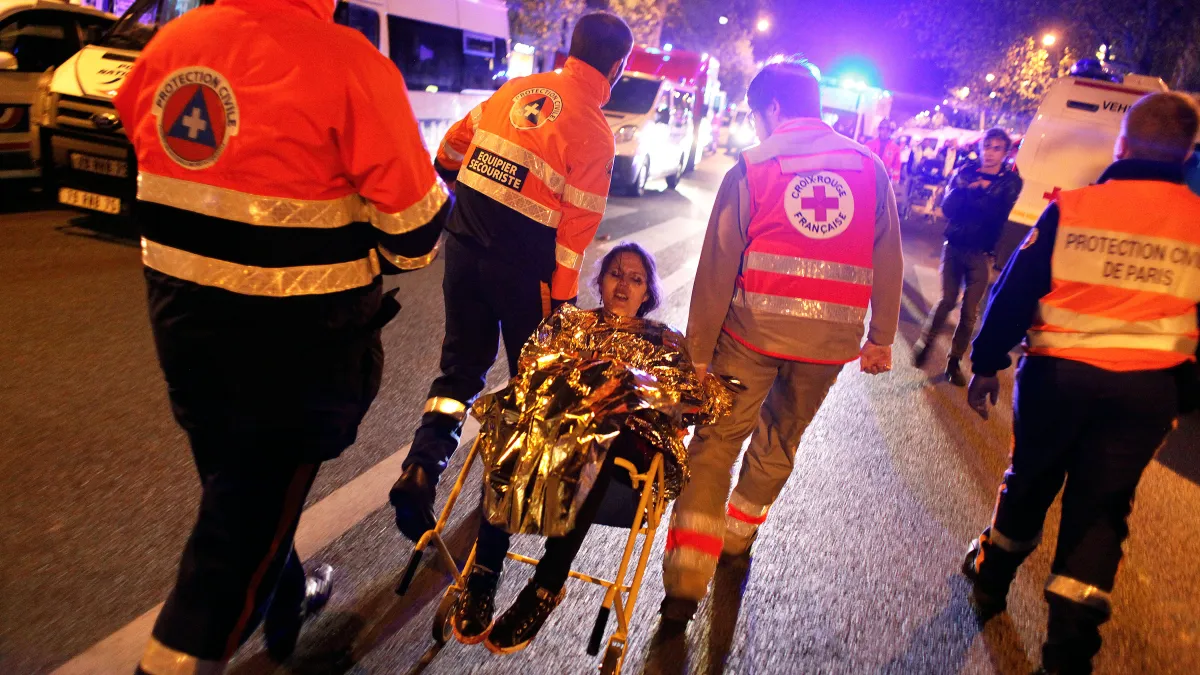 巴黎恐怖攻擊。在巴塔克蘭劇院(Bataclan)外,警消人員正在疏散人群,把一名女子帶到安全處。(美聯社)