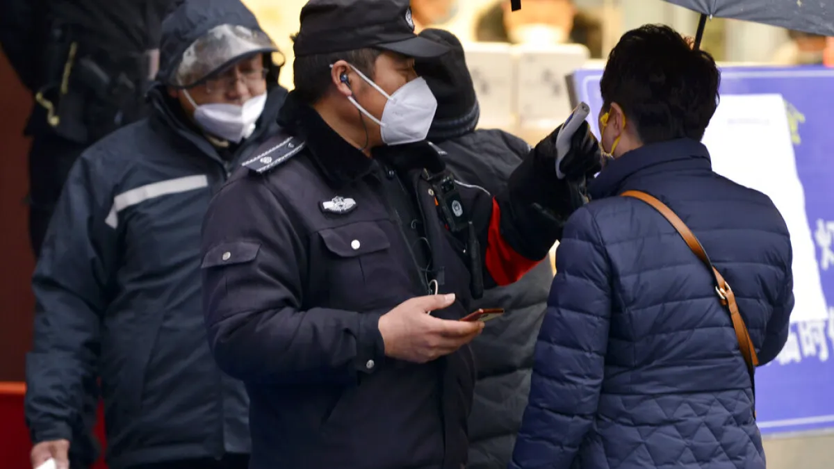 武漢肺炎疫情肆虐,南京市4日晚間發布公告全面實行「小區封閉管理」。圖為警察在秦淮區為往來民眾檢查體溫。(美聯社)
