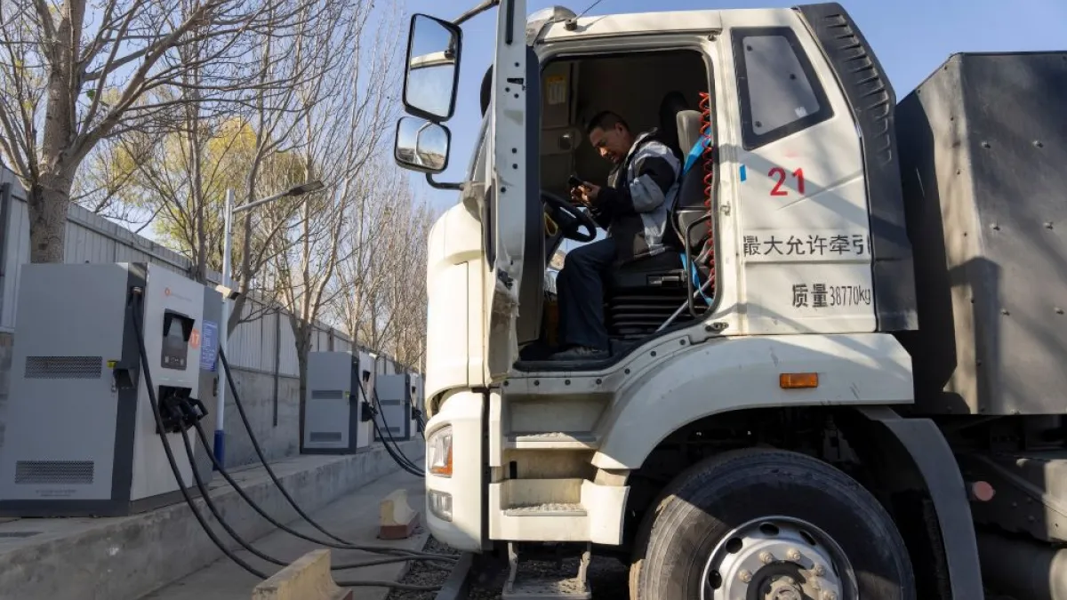 一名貨車司機在充電站為他的電動卡車充電。(美聯社)