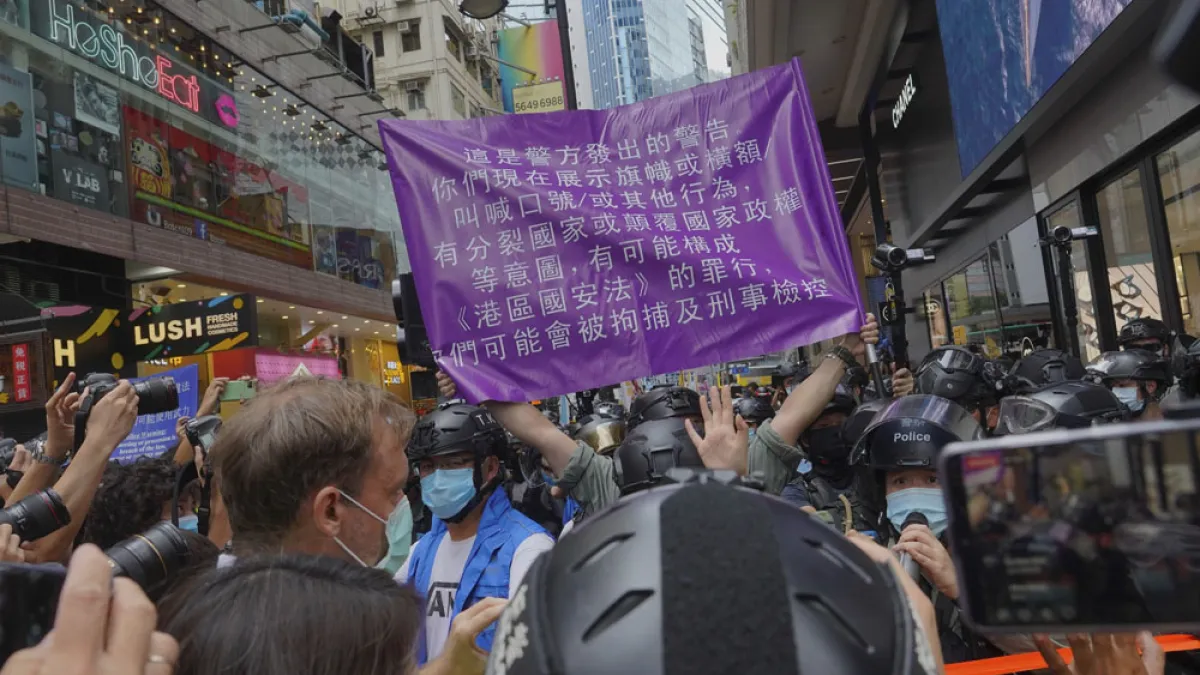 港警舉著「紫旗」警告民眾違反《港區國安法》,反遭民眾嘲笑。(美聯社)
