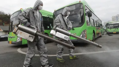 南韓武漢肺炎確診人數已衝破千人大關,圖為穿著防護服的工作人員在首爾巴士總站進行消毒。(美聯社)