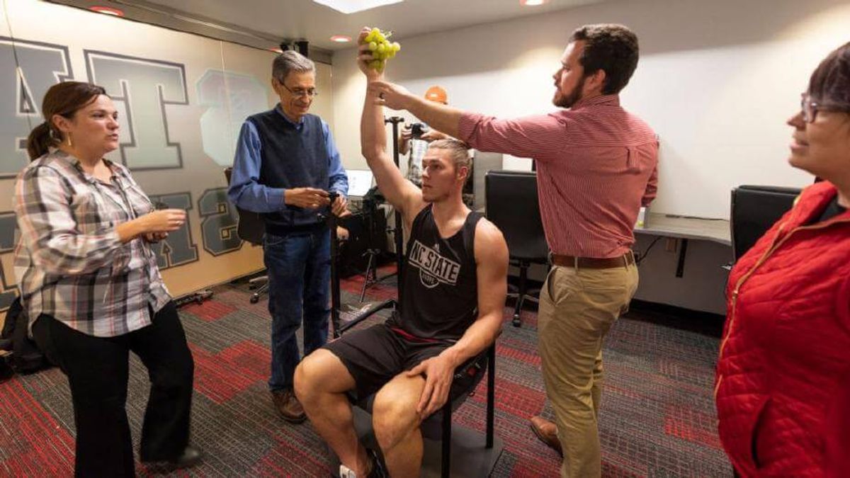 此圖為Walker在位於羅里(Raleigh)的球隊籃球中心練習場模擬拿著葡萄的姿態,修復團隊們從旁協助Walker將手臂的位置調整成符合Bacchus雕像的樣子。(圖/取自Artnet News,非池中藝術提供) 此圖為Walker在位於羅里(Raleigh)的球隊籃球中心練習場模擬拿著葡萄的姿態,修復團隊們從旁協助Walker將手臂的位置調整成符合Bacchus雕像的樣子。(圖/取自Artnet News,非池中藝術提供)