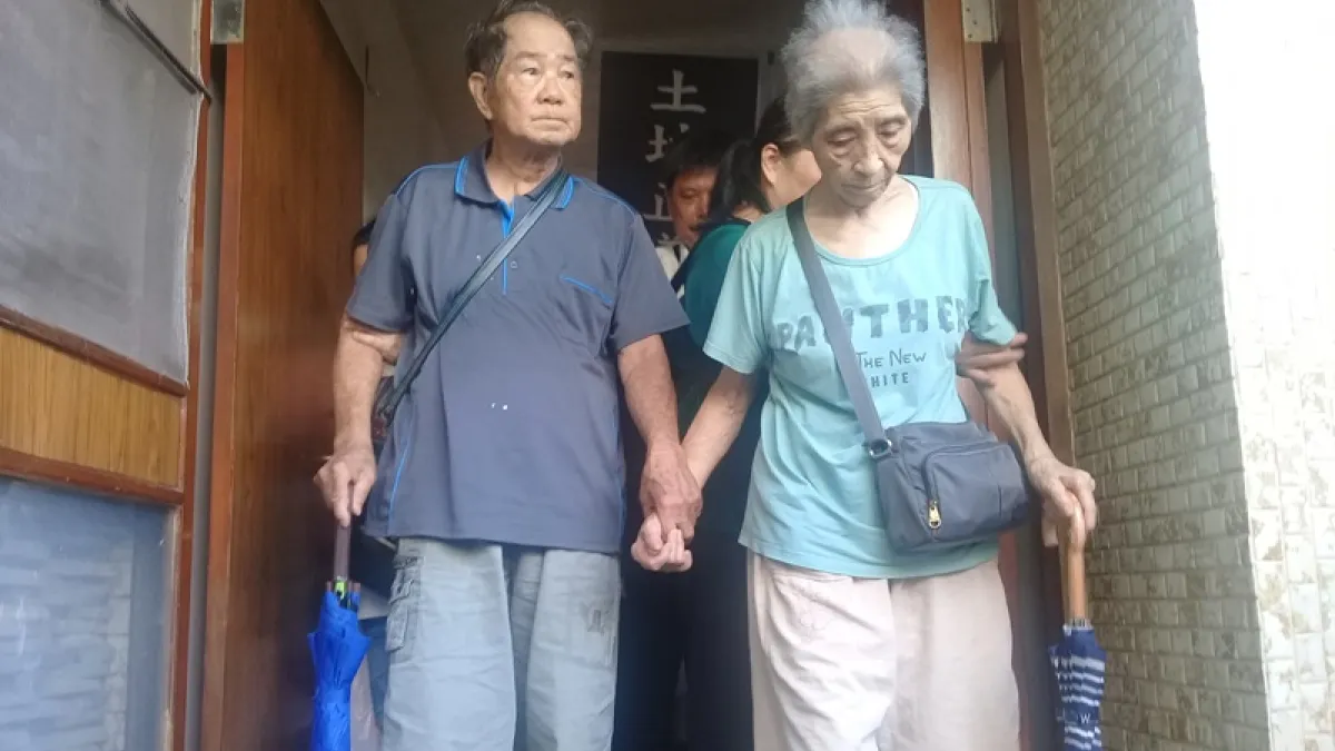 南鐵陳家2020年10月13日被強拆,陳蔡信美牽著失智先生陳割的手,離開住了半世紀的家。(朱淑娟提供)