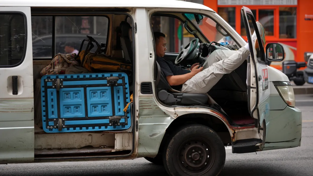北京一名貨運公司員工在停放路邊的貨車裡休息。(資料照,美聯社)