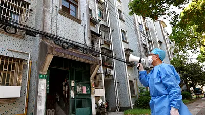 2022年4月12日,上海的防疫人員正在用大聲公對居民宣達防疫措施。(美聯社)