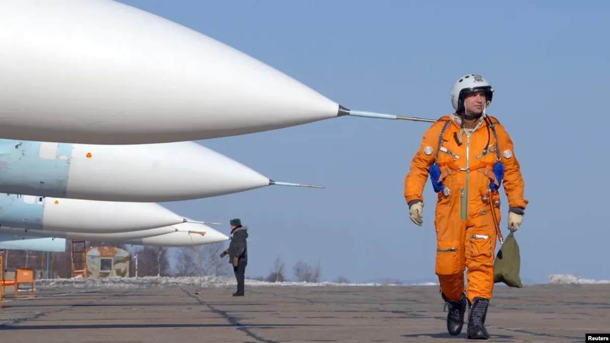 一名飛行員走過在俄羅斯一個空軍基地的停放的蘇-27戰鬥機。(美國之音)