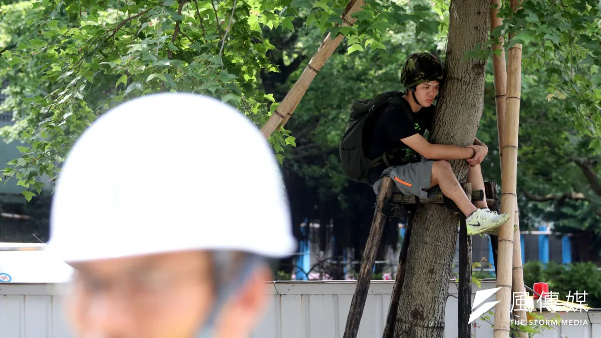 台北市政府、遠雄今天將進行大巨蛋周圍33棵行道樹斷根工程,護樹團體不滿遠雄公安未改善完成、也未重新議約就要移樹,在遠雄、市府人員現勘時,爬上樹抗議。(蘇仲泓攝)