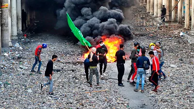 今年全球都不平靜,天災之外,示威抗議遍及各國。圖為伊拉克示威者遭當局開槍鎮壓。(AP)