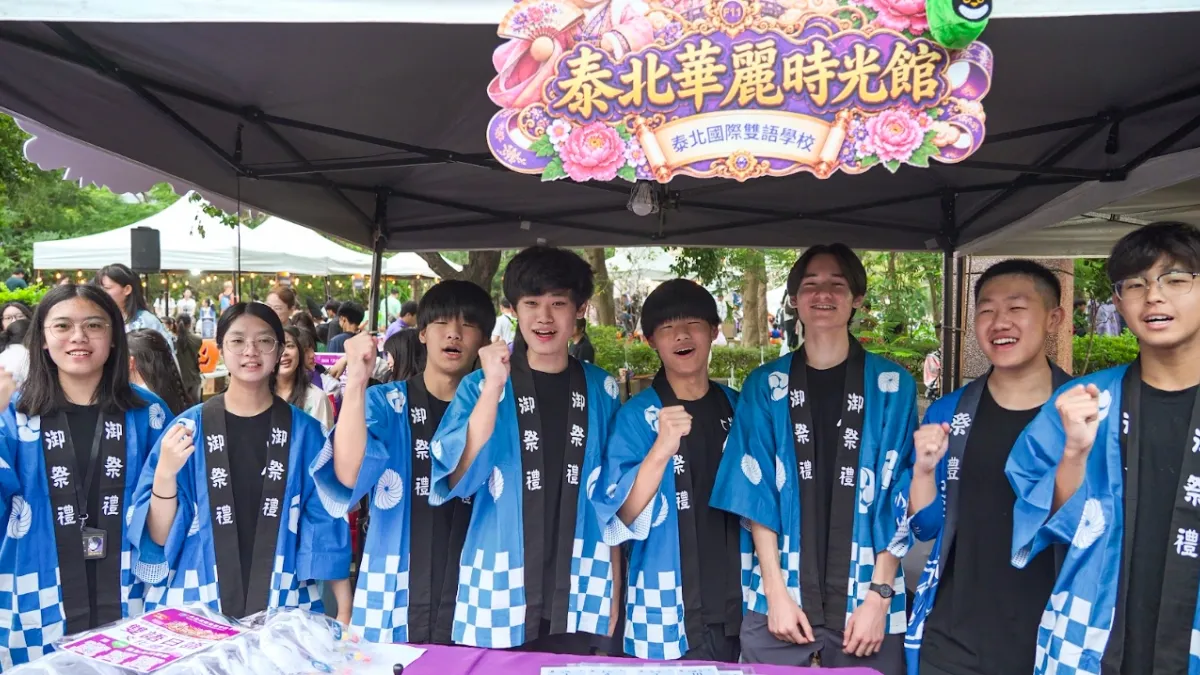 泰北學生穿上藍色祭典服裝,在活動攤位前合影,展現服務熱情。(圖/泰北國際雙語學校提供)