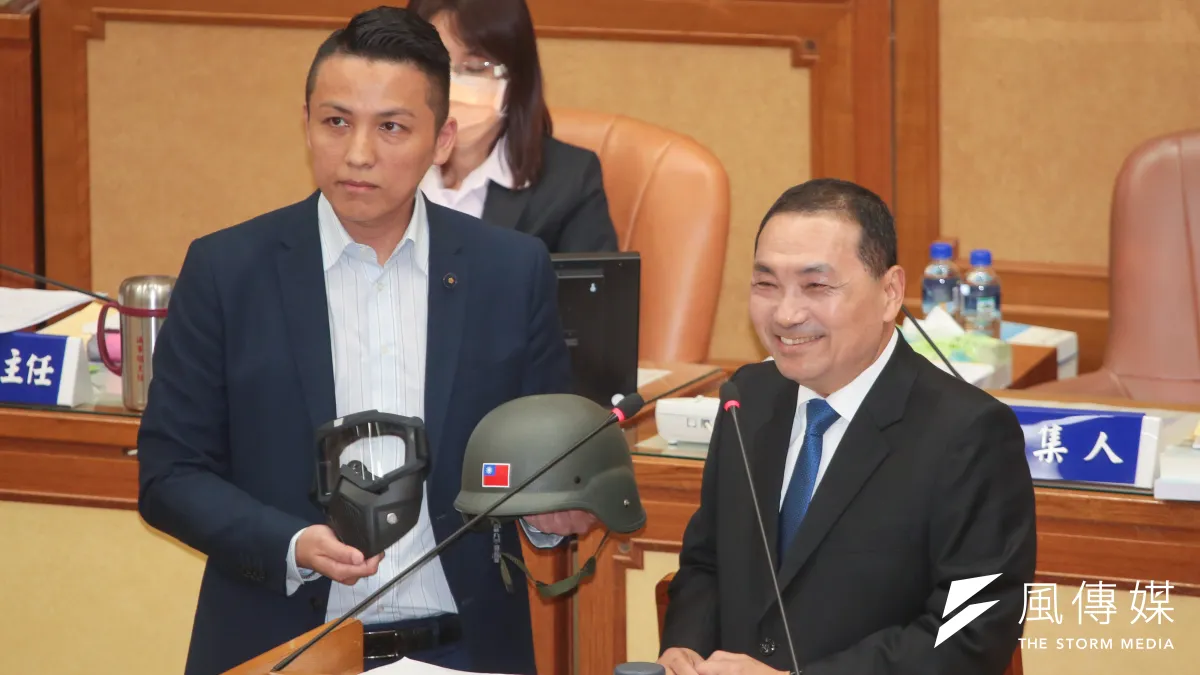 新北市長侯友宜(右起)26日至新北市議會進行施政報告,國民黨新北市議員陳偉杰送上頭盔、面罩,盼助侯「勇往直前」。(顏麟宇攝)