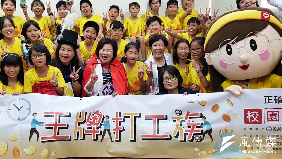 勞動部長許銘春(披紅披肩者)與國小學子共同觀賞蘋果劇團演出的「王牌打工族」。(圖/方詠騰攝)