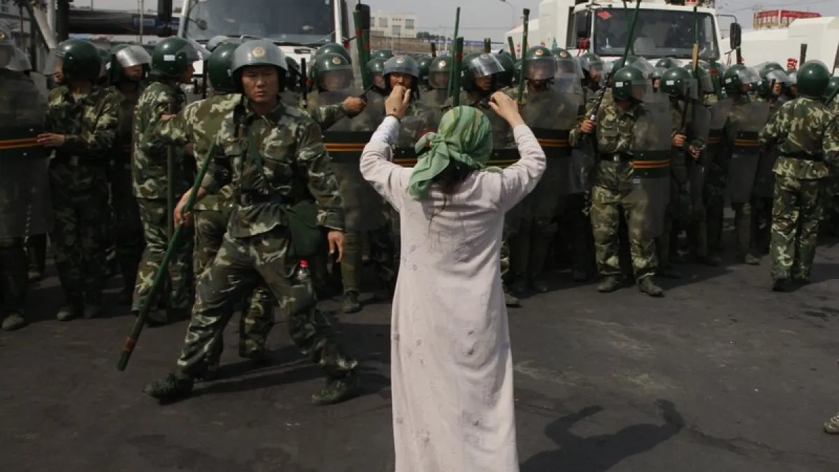 圖為七五事件後兩日,一名維吾爾婦女在武警面前抗議。(AP)