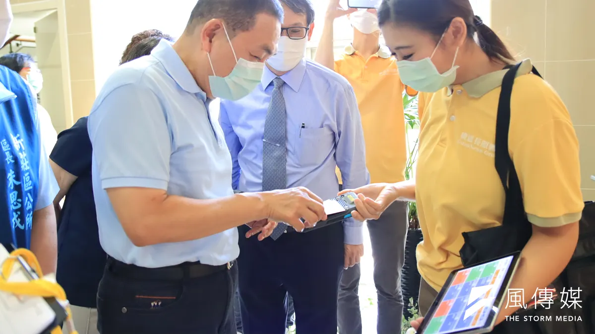 市長侯友宜試用刷卡、溫度監測上傳雲端,家屬可透過app了解家屬動向及體溫。(圖/新北市衛生局提供)