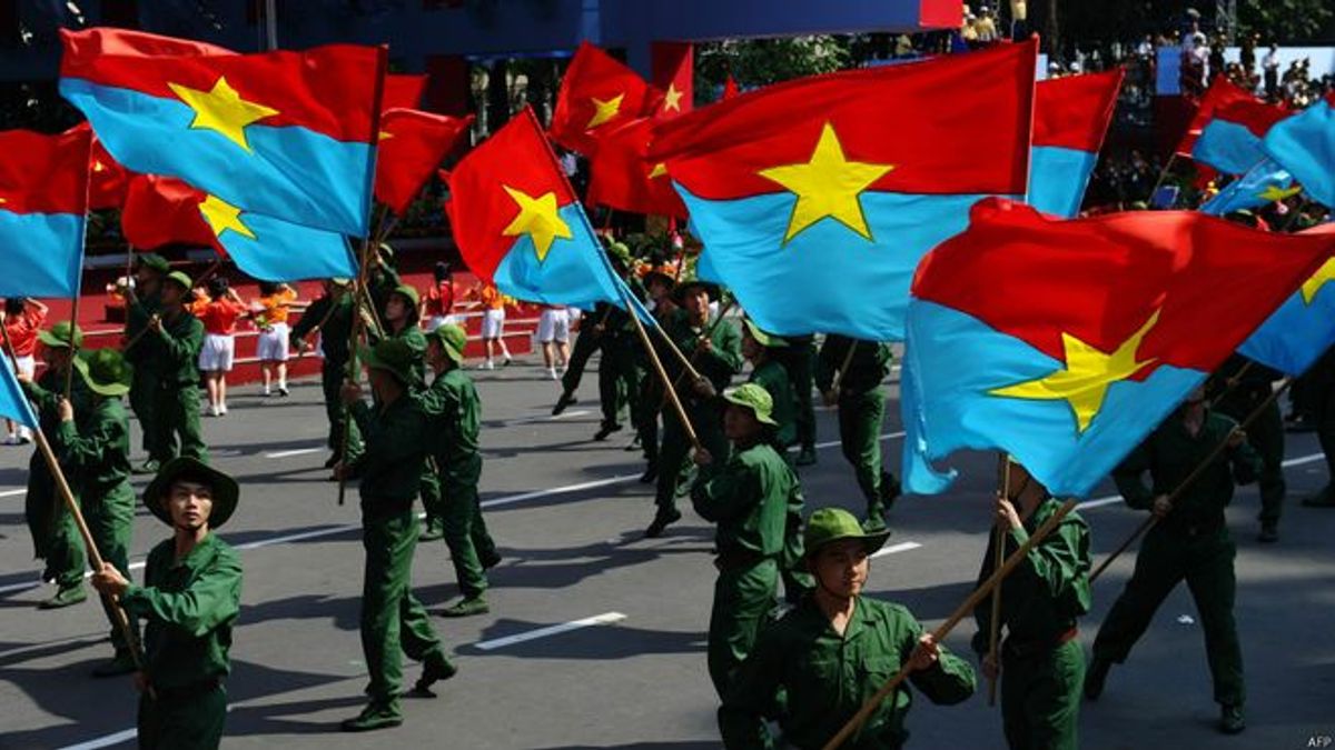 閱兵式上有學生揮舞「越南南方民族解放陣線」旗幟。西方社會認識的簡稱「越共」一般是指這支由越南共產黨指揮的游擊隊。 閱兵式上有學生揮舞「越南南方民族解放陣線」旗幟。西方社會認識的簡稱「越共」一般是指這支由越南共產黨指揮的游擊隊。