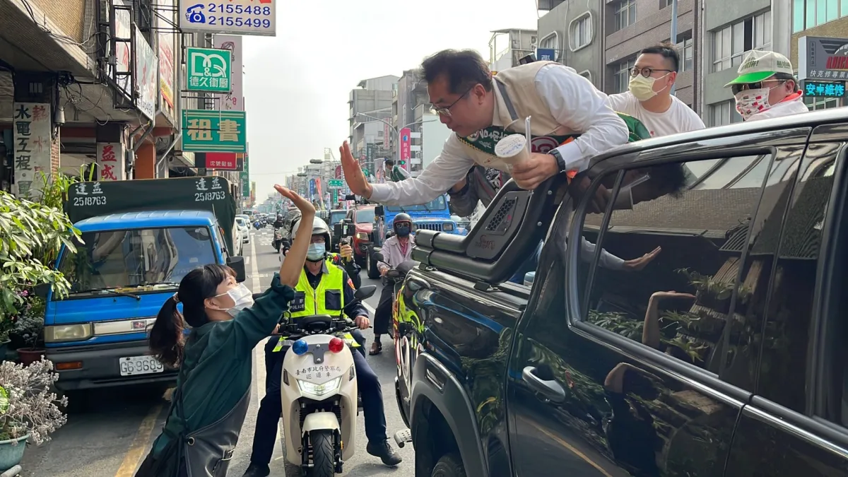 一名熱情的店員雙手舉起珍珠奶茶要送給市長,黃偉哲彎下腰接受店員的慰勞,並與店員擊掌說謝謝。(圖/黃偉哲競總提供)