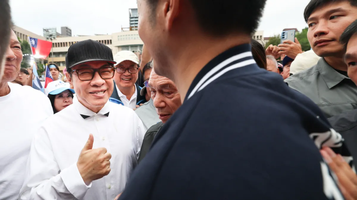 2026年10月26日,台北市長蔣萬安(前背對者)在敦化國中舉行競選總部成立大會,上前致意,藝人蔡康永(左黑帽者)比讚互動。(中央社)