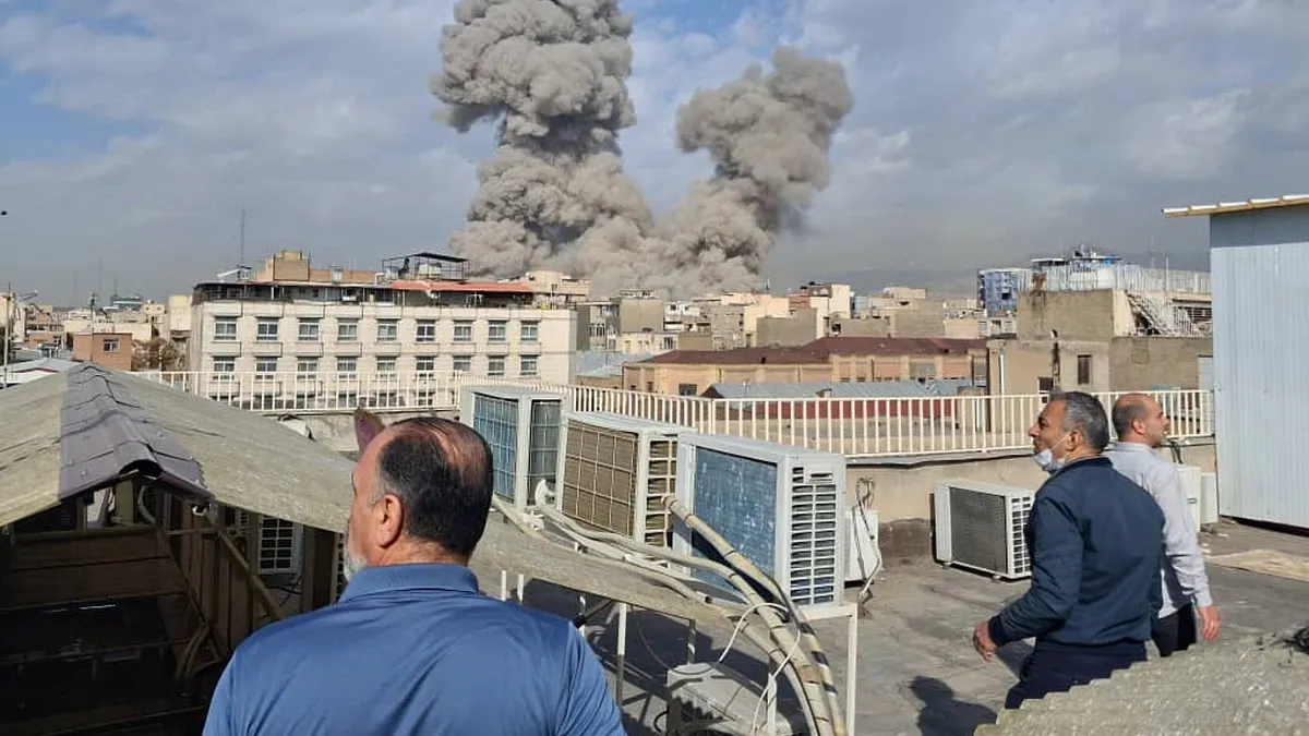 2026年2月28日,伊朗德黑蘭發生爆炸後,民眾看著天際線升起濃煙。(美聯社)