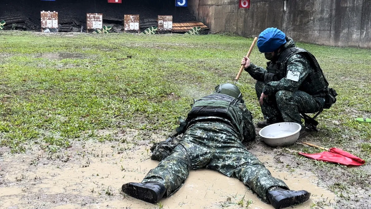 手持T91步槍臥射的召員,整個人趴在積水泥濘中射擊,無畏風雨投入訓練。(陸軍第八軍團提供)