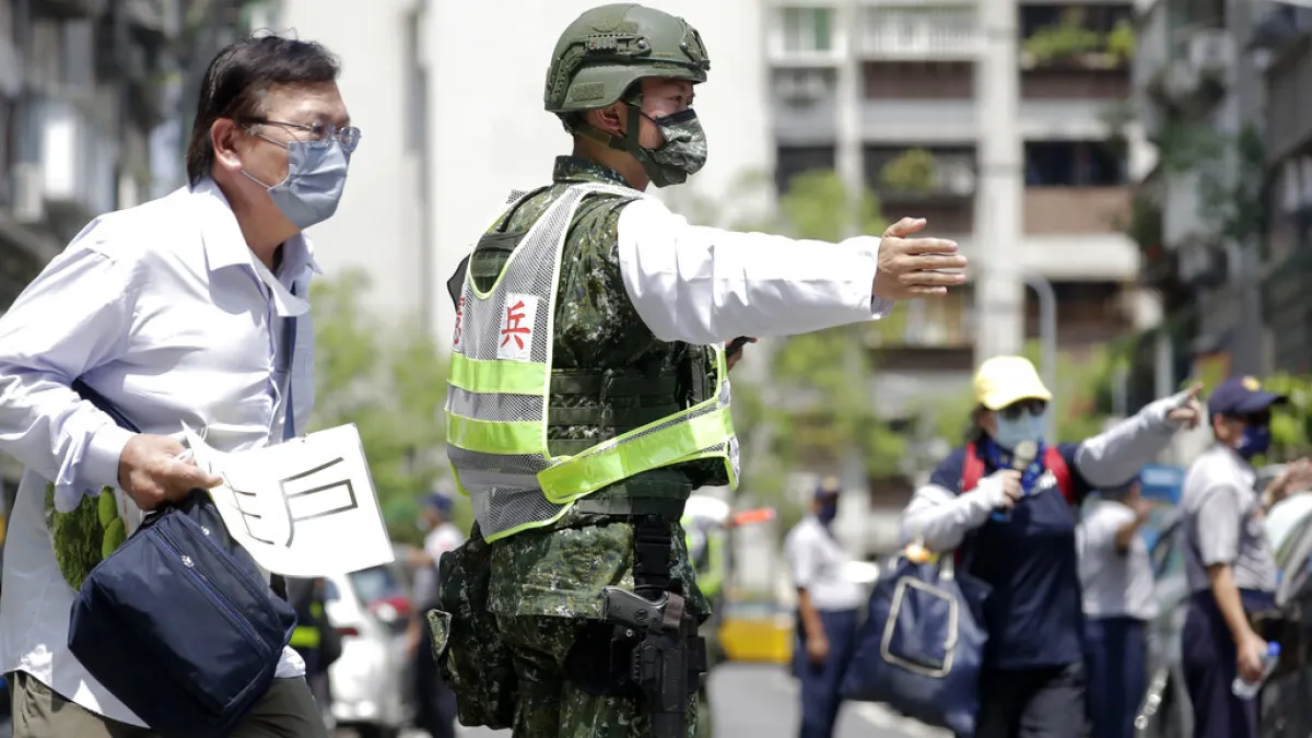 2022年7月25日,台灣舉行萬安45號演習,一名軍人正在引導台北市民進入避難所避難。(美聯社)