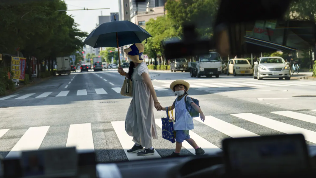 東京一位媽媽牽著孩子過馬路。(美聯社)