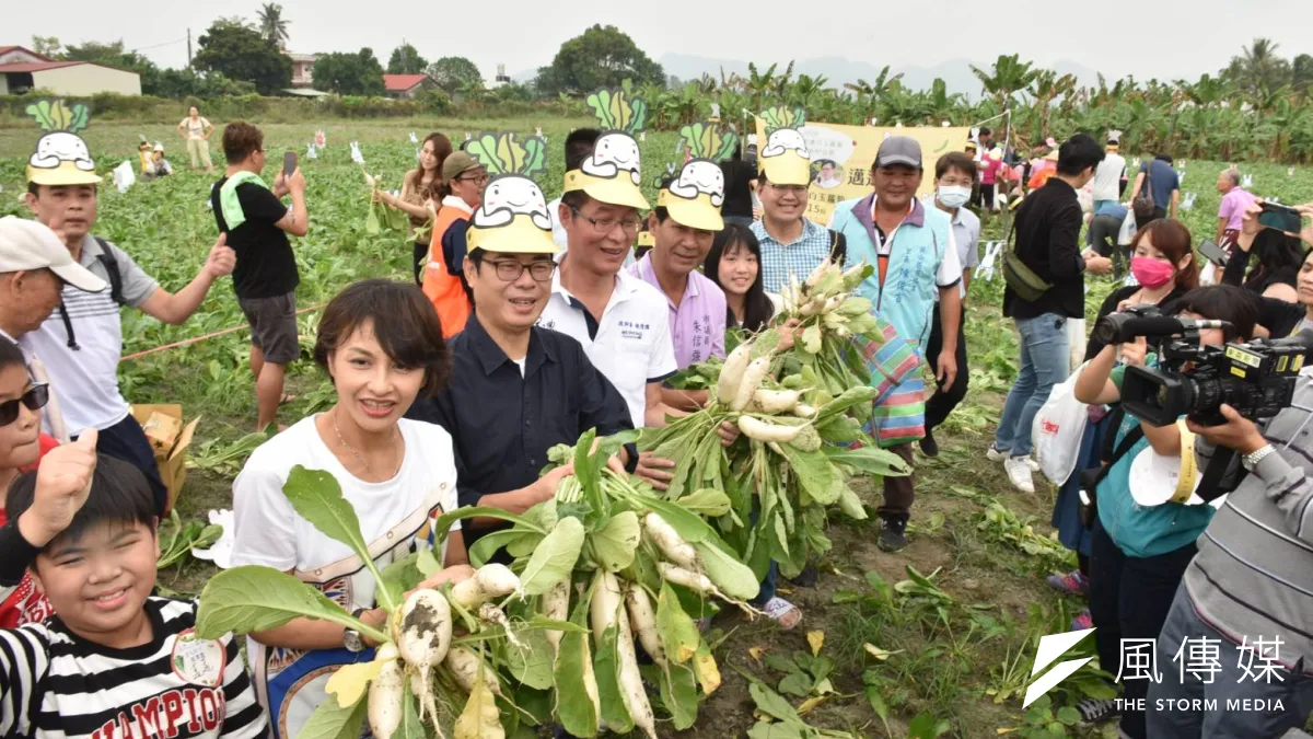 高雄市長陳其邁(左三)對於白玉蘿蔔的清甜爽脆讚不絕口,高舉蘿蔔與滿園的大小民眾合影,大力推廣冬日的好滋味。(圖/徐炳文攝)