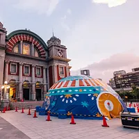 台湾各地で人気を集めてきた「移動する物語の館」が、大阪市中央公会堂の外、癒し系のa-Weの隣に巨大テントを設置。夕暮れ時の幻想的な空の下で、ひときわ注目を浴びている。 台湾各地で人気を集めてきた「移動する物語の館」が、大阪市中央公会堂の外、癒し系のa-Weの隣に巨大テントを設置。夕暮れ時の幻想的な空の下で、ひときわ注目を浴びている。