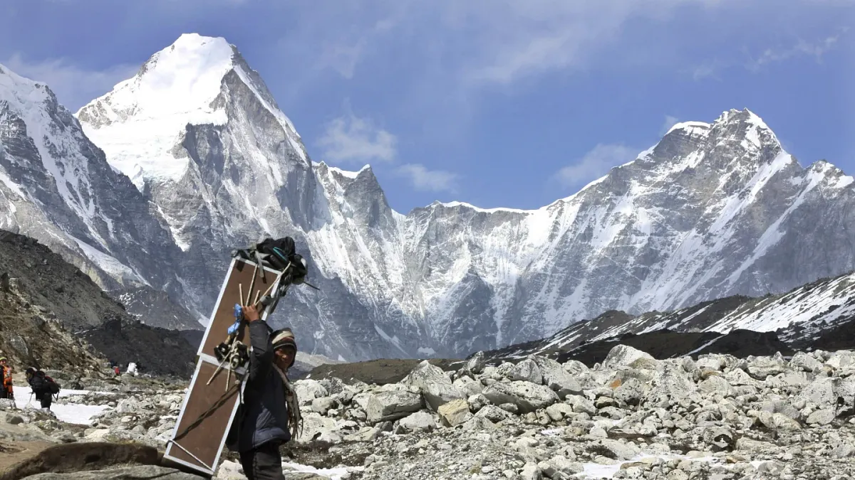 2015年4月10號。一名雪巴人背著裝有氧氣瓶的箱子,朝聖母峰基地營的方向前進。(AP)