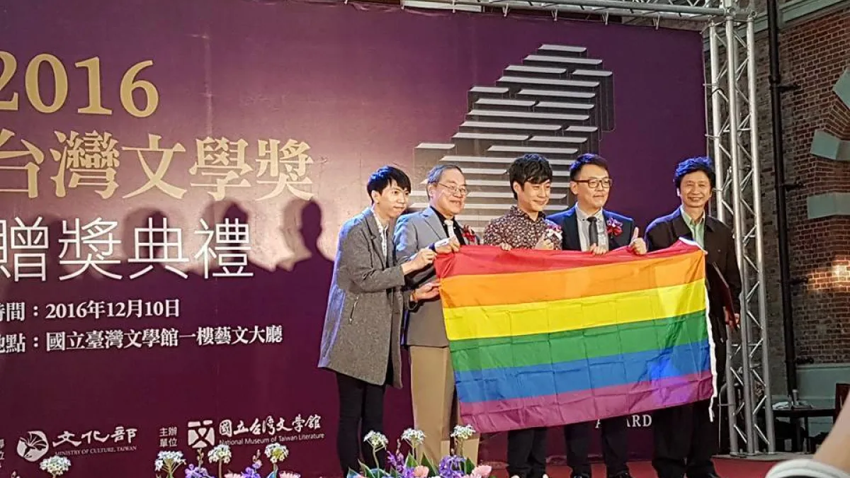 台灣文學獎頒獎典禮,陳栢青(中)舉彩虹旗上台領獎。(取自陳栢青臉書)