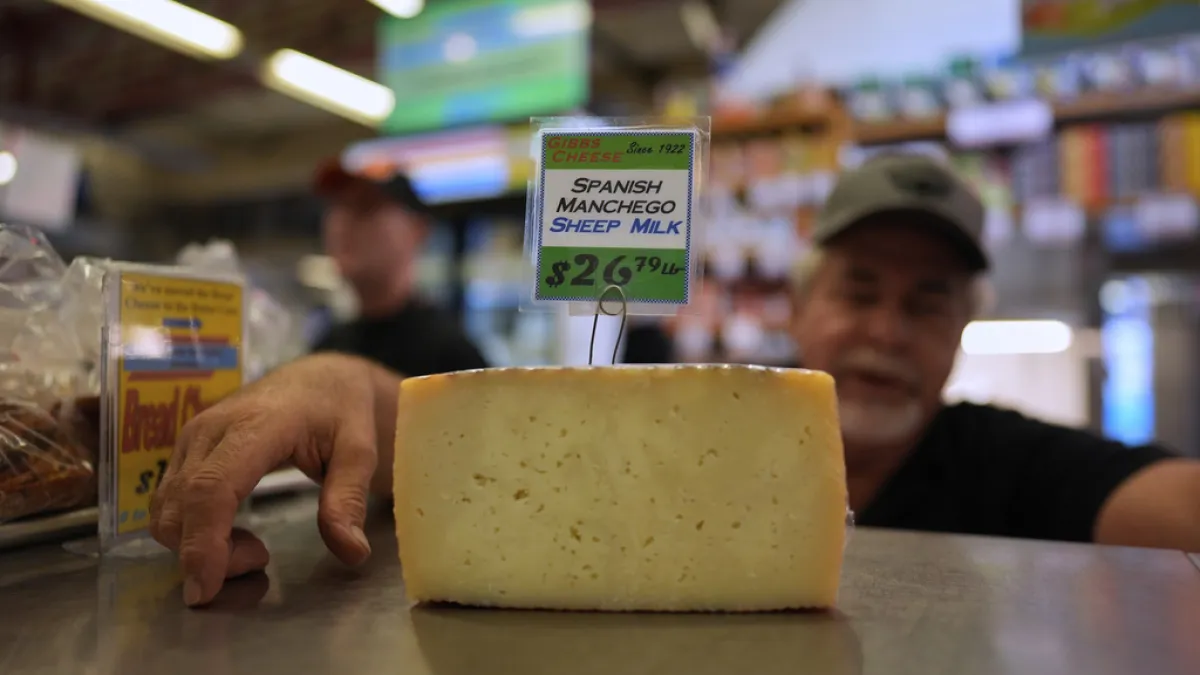 2025年4月3日。吉布斯乳酪(Gibbs Cheese)的老闆Jeff Gibbs在辛辛那提芬德利市場的商店裡展示了一塊從西班牙進口的西班牙曼切戈乳酪。(AP)關稅