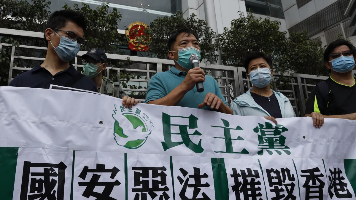 中國授權人大常委制定「港版國安法」,香港民主黨人士到中聯辦前拉布條抗議。(AP)