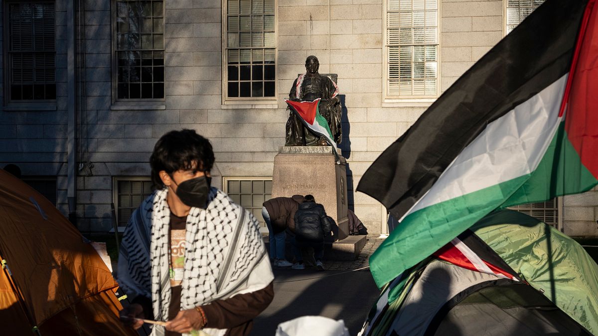 2024年4月25日,一名學生在哈佛大學捐助者約翰·哈佛的雕像前,披著巴勒斯坦旗幟參加反對加薩戰爭的示威。(美聯社) 2024年4月25日,一名學生在哈佛大學捐助者約翰·哈佛的雕像前,披著巴勒斯坦旗幟參加反對加薩戰爭的示威。(美聯社)
