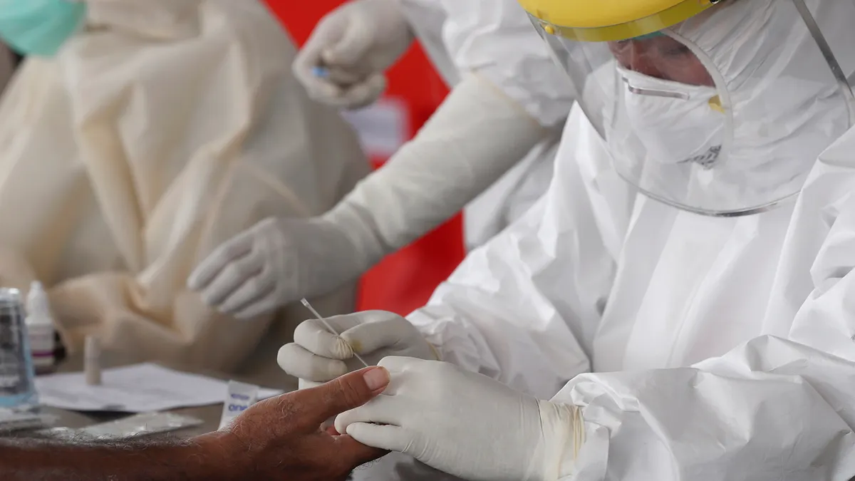 印尼的武漢肺炎疫情延燒,衛生人員為一名男子做血液快篩(美聯社)