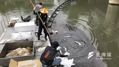 環保局人員以吸油棉清除河面上油汙。(圖/徐炳文攝)