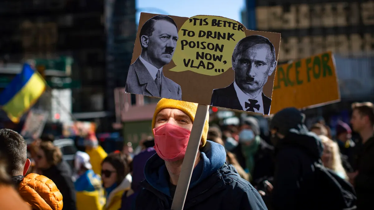 普京正式下令對烏克蘭動武後,歐洲各地當天就出現抗議人潮,許多民眾將普京與納粹魔頭希特勒的照片並列。(美聯社)