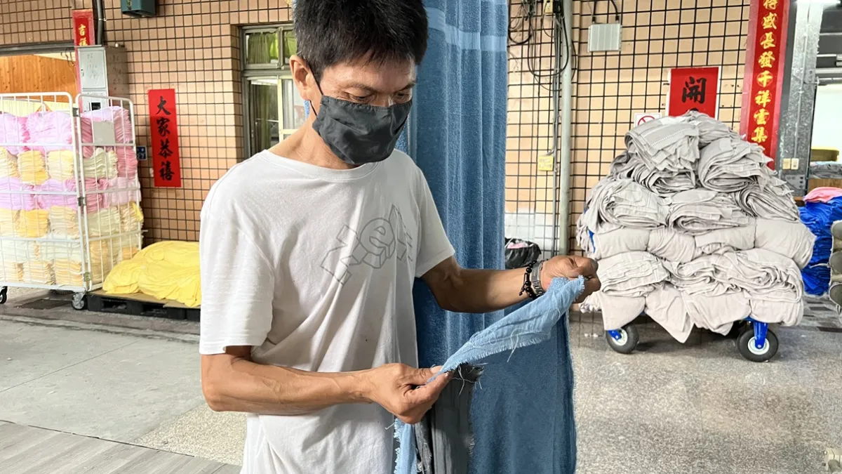 左明燦細心檢查毛巾材料,準備入機器裁縫。(圖/虎尾就業中心提供)