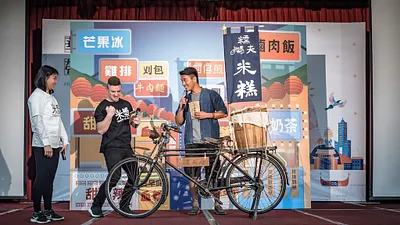 台南知名小吃糯夫與知名YouTuber小貝(Logan D. Beck)共同演示「華語101」教材之內容。(圖/教育部提供)