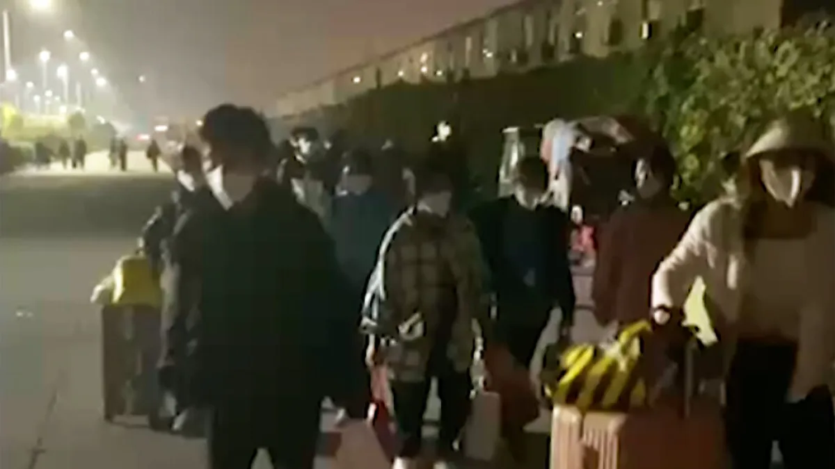 2022年10月29日,許多富士康員工提著行李離開鄭州園區。(美聯社)