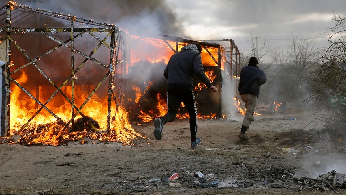 加萊移民跑經燃燒中的搭建屋(美聯社) 加萊移民跑經燃燒中的搭建屋(美聯社)