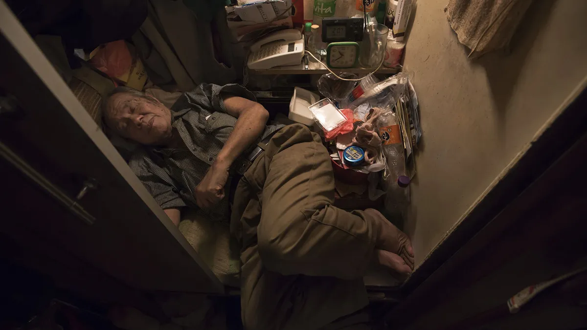 超過20萬香港人住在非法劏房裡,80歲的張先生睡在劏房裡,甚至無法將腳伸直(美聯社)