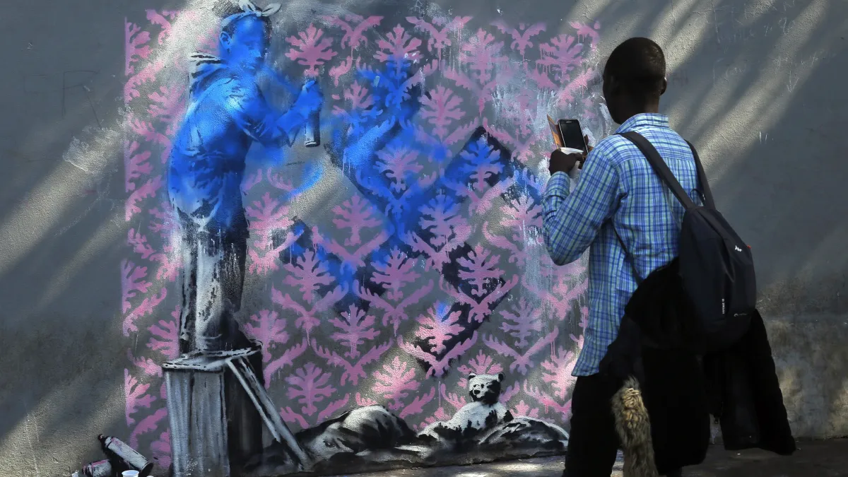 2018年6月25日,民眾於英國知名街頭藝術家班克西(Banksy)在巴黎的最新塗鴉前拍照。(AP)