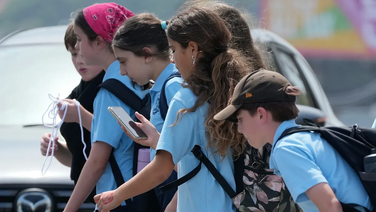 澳洲雪梨,放學途中滑手機的女孩。(美聯社)