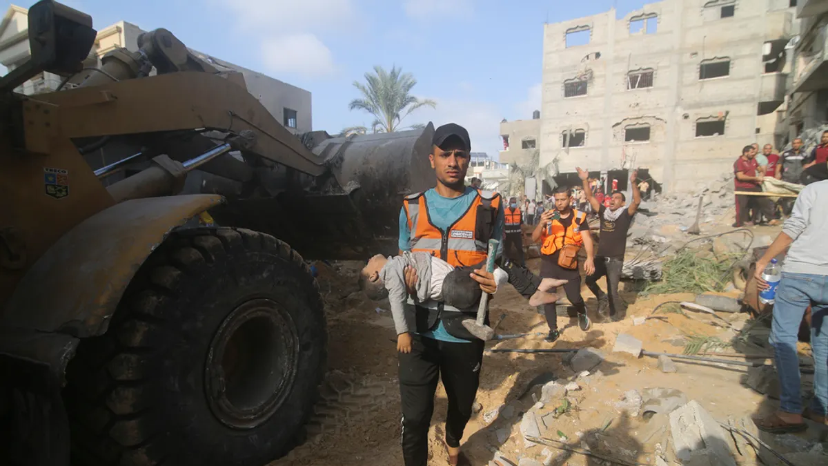 2023年10月24日,以色列襲擊加薩走廊拉法後,巴勒斯坦人從廢墟中救出一名男孩。(美聯社)