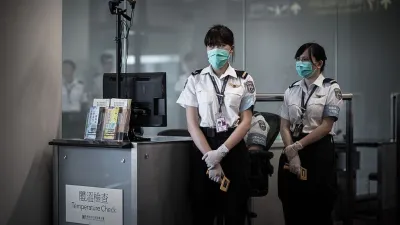 Airport personnel wait for passengers to check their temperature as part of preventive measures against the spread of Middle East Respiratory Syndrome (MERS) at the Hong Kong international airport on June 5, 2015.