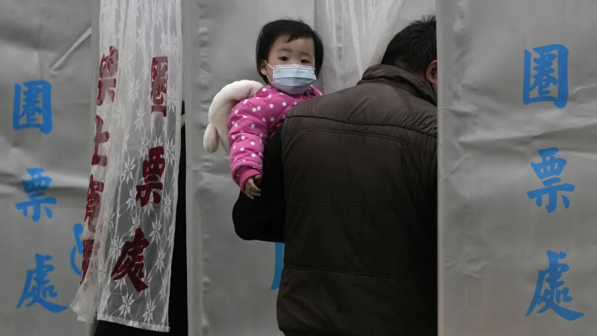2024年1月13日,台灣舉行總統暨國會大選,一位抱著女兒的民眾正在投票所投票。(美聯社)