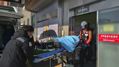 2024年12月29日,韓國務安國際機場發生空難,救援人員正在將生還者送醫。(美聯社)