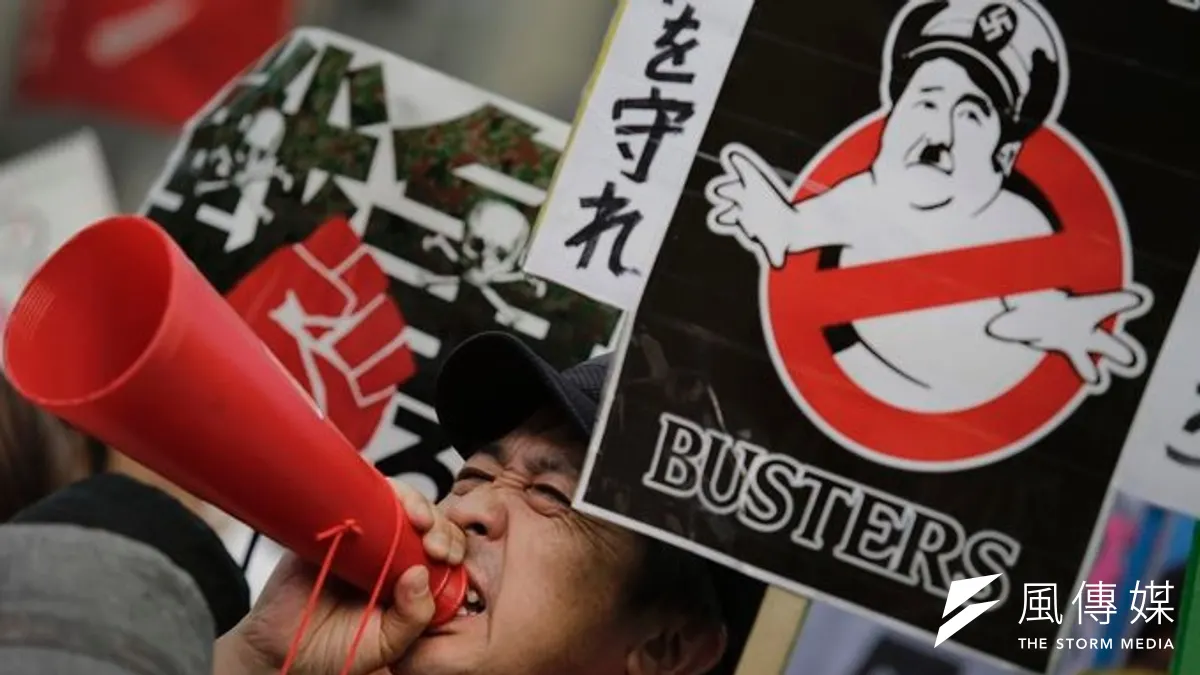 反對解禁集體自衛權的日本民眾,將首相安倍晉三醜化為希特勒。(美聯社) 反對解禁集體自衛權的日本民眾,將首相安倍晉三醜化為希特勒。(美聯社)