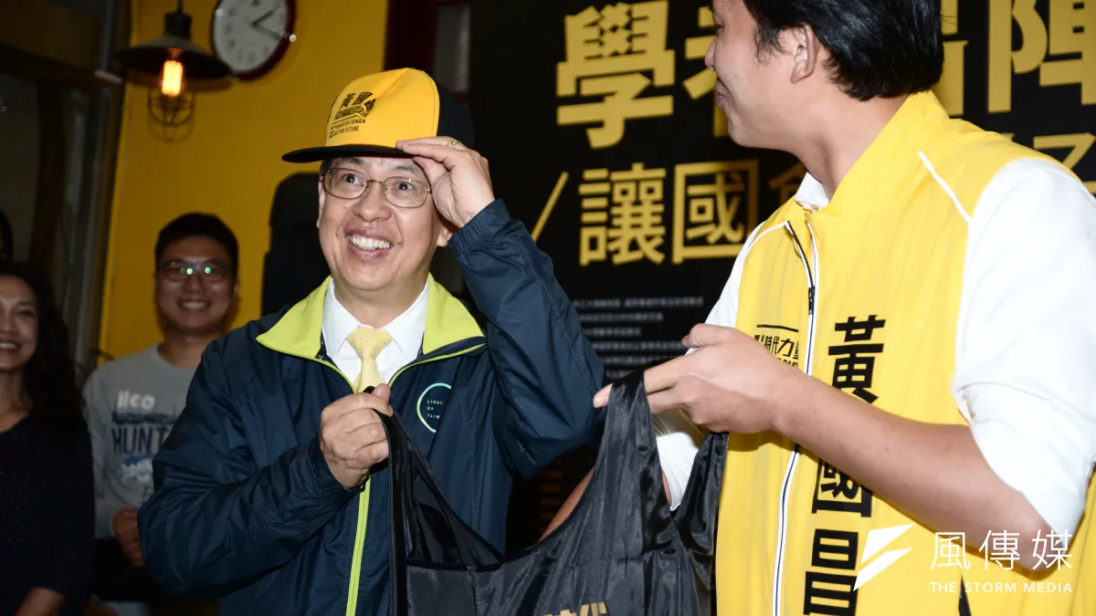民進黨副總統候選人陳建仁出席黃國昌總部記者會,陳馬上從黃贈送的暖暖袋中拿起鴨舌帽試戴。(林俊耀攝)