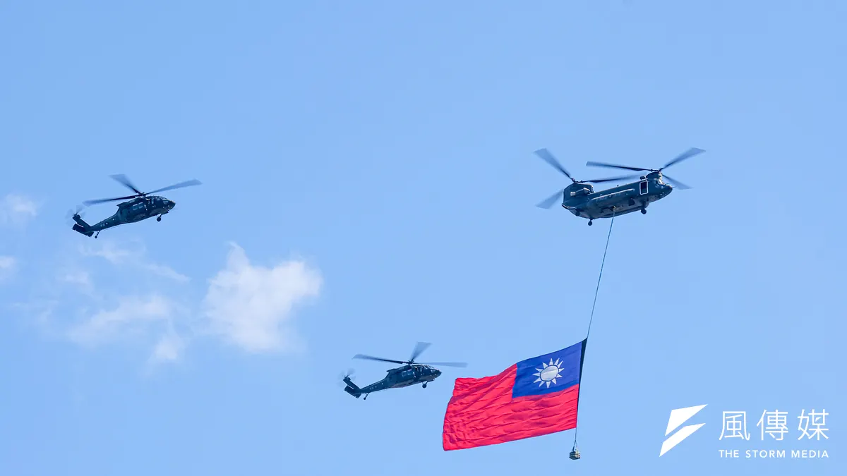 114年國慶大會10日於總統府前舉辦,空中一架吊掛國旗的契努克運輸直升機於兩架黑鷹直升機護航下飛行。(劉偉宏攝)