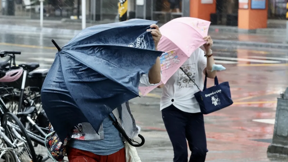 台風30号(チャンパー)の接近で、強い風雨の中を傘を差して歩く人たち。(中央社)
