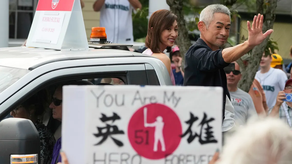 2025年7月26日、クーパーズタウンでの野球殿堂伝説の人物パレードで、鈴木一朗と妻の鈴木弓子さんがファンに手を振っている。(AP通信) 2025年7月26日、クーパーズタウンでの野球殿堂伝説の人物パレードで、鈴木一朗と妻の鈴木弓子さんがファンに手を振っている。(AP通信)